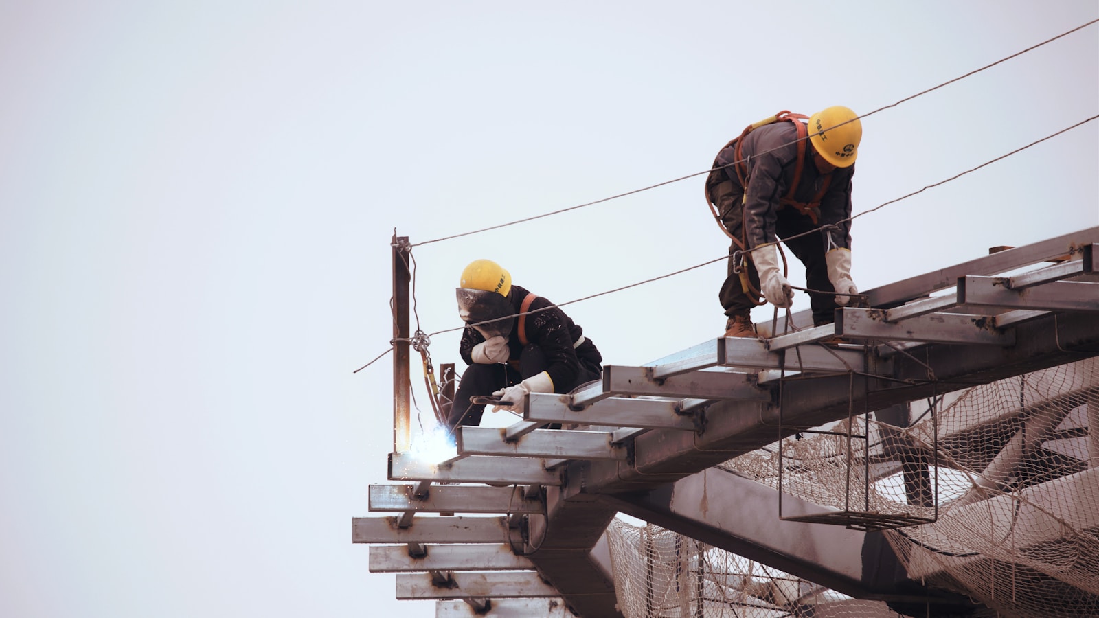 man in black jacket and yellow hard hat standing on top of building during daytime, workers' comp & OSHA